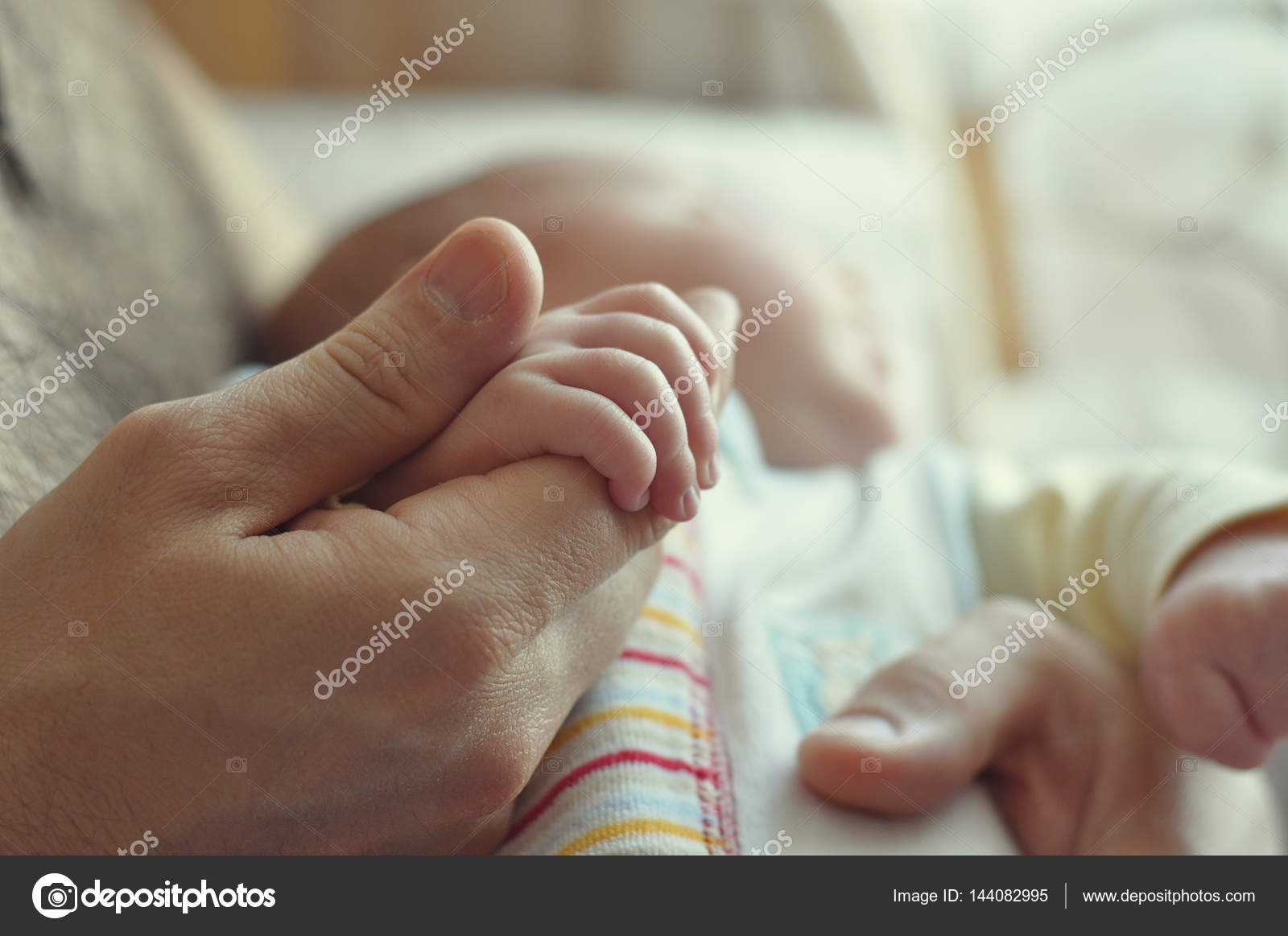 A father holds his baby's hand